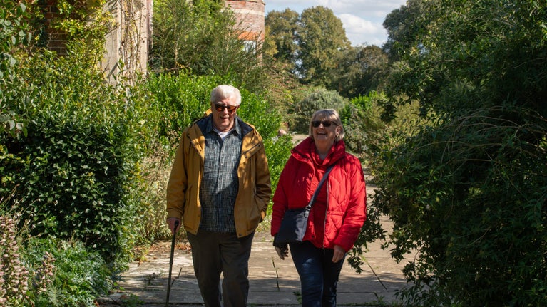 Two visitors in raincoats exploring the autumnal garden at Hinton Ampner, Hampshire